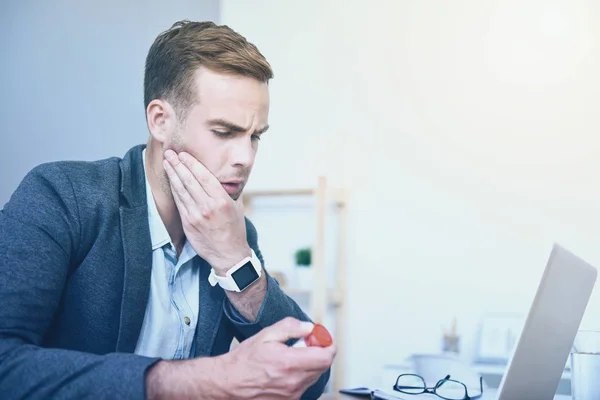 Gut aussehender unzufriedener Mann mit Kopfschmerzen am Arbeitsplatz. — Stockfoto