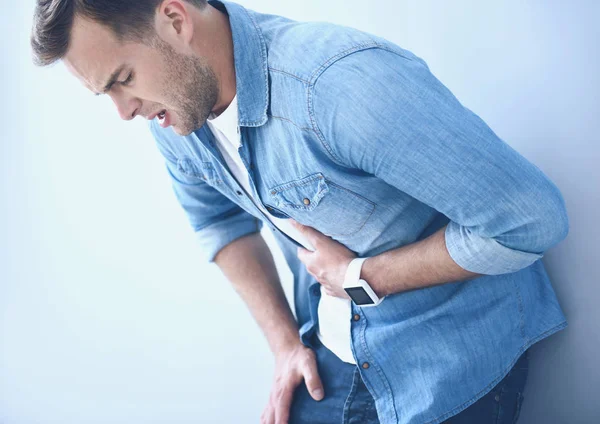 Müder junger Mann mit Bauchschmerzen nahe der Mauer. — Stockfoto