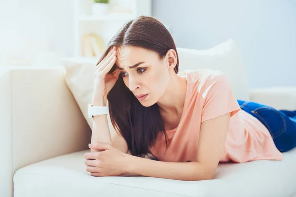 Junge enttäuschte Frau liegt auf dem Sofa. — Stockfoto