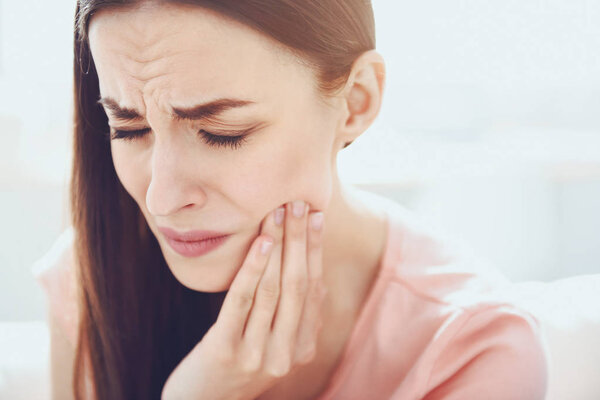 Close up of young unhappy woman which having toothache.