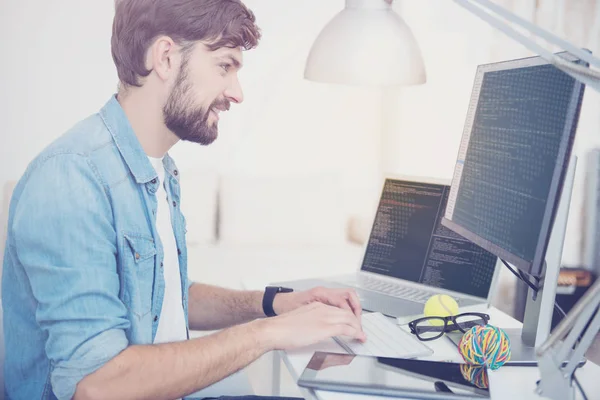 Sorrindo homem programação em um escritório acolhedor — Fotografia de Stock