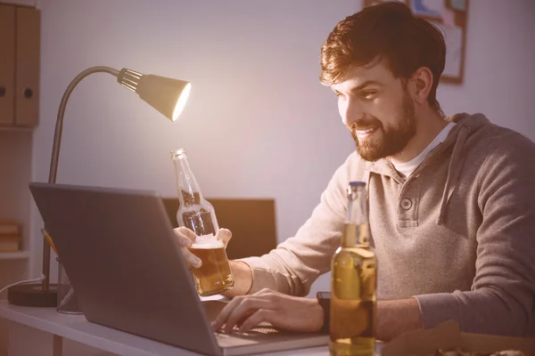 Mann benutzt Laptop und trinkt ein Getränk — Stockfoto