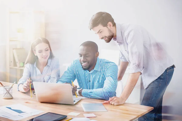 Travailleurs souriants utilisant un ordinateur portable au bureau — Photo