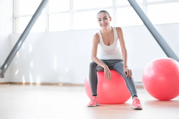 Mycket nöjd bra byggd kvinna sitter på en rosa fitness boll — Stockfoto