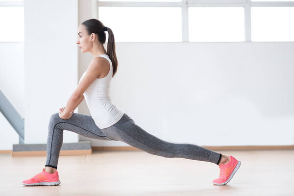 Confident slim woman exercising on a sports hall