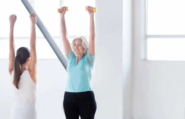 Athletic slim woman holding small dumbbells up — Stock Photo, Image