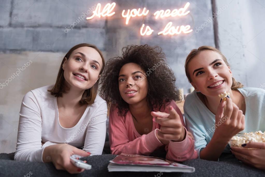 Positive young girls discussing film lying on the bed — Stock Photo