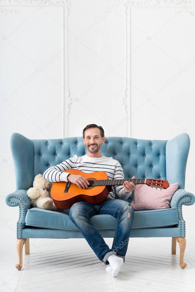 Positive cheerful man playing the guitar