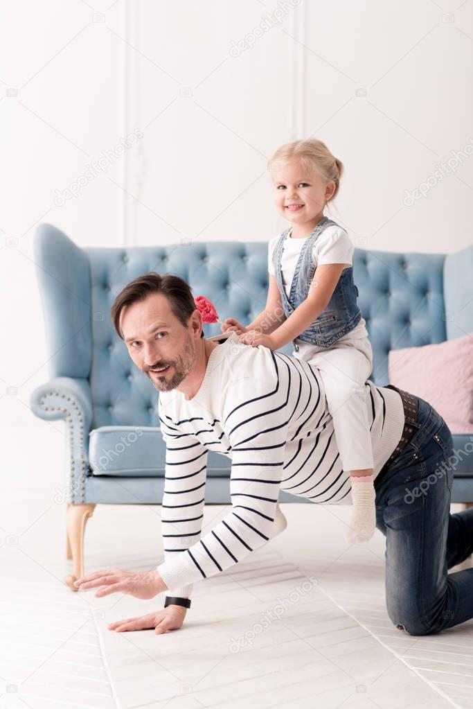 Happy pretty girl sitting on her fathers back