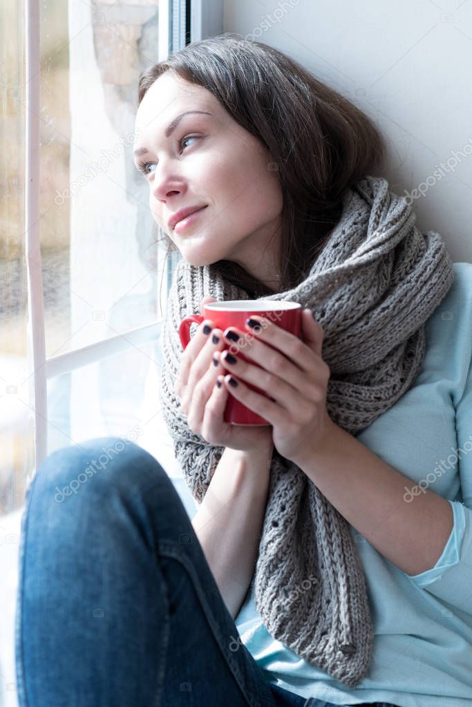 Calm dreamy woman leaning on the window glass