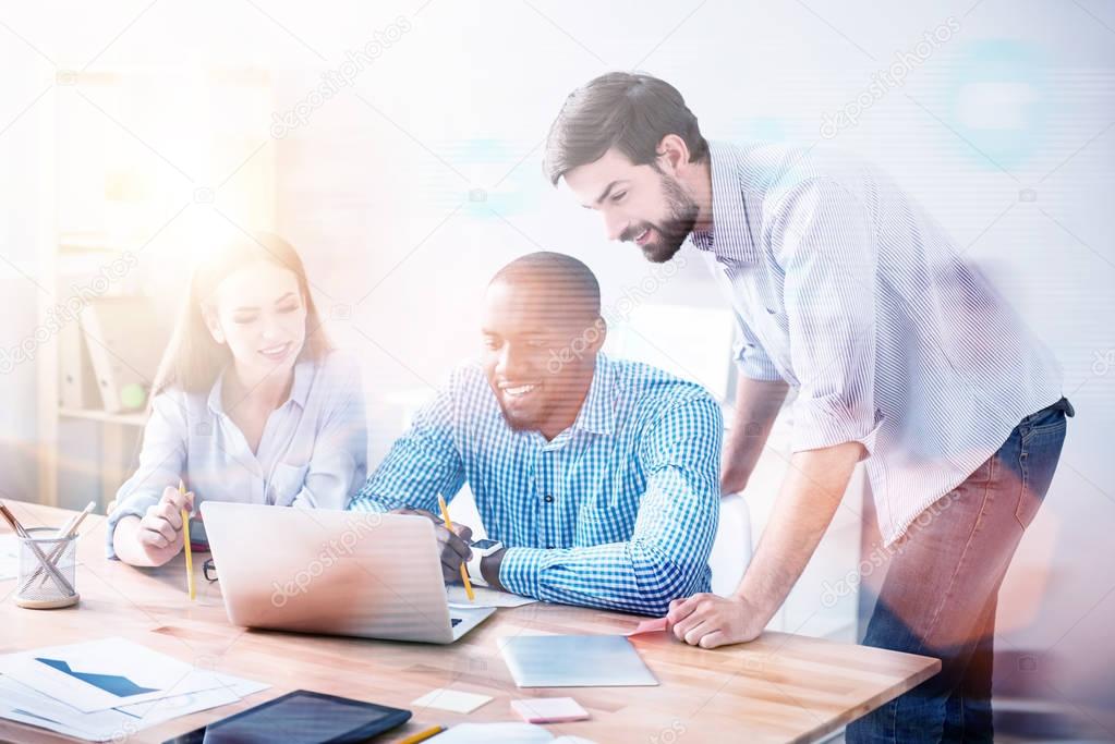 Smiling workers using laptop in office