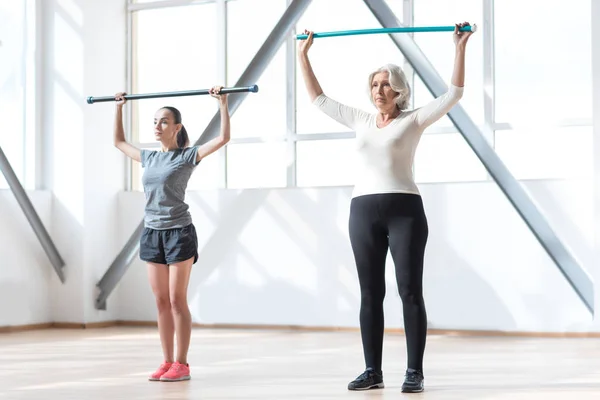 Mujeres serias confiadas haciendo ejercicio con un bastón de gimnasia — Foto de Stock