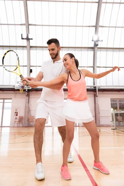 Cheerful tennis instructor teaching young woman