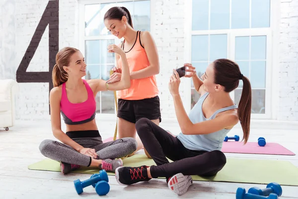 Tre glada kvinnor kontroll deras träningsresultat i gymmet — Stockfoto