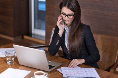 Konsantre kadın bir ofiste bir cep telefonu üzerinde söz