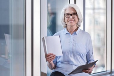 Yaşlı kadın bir ofiste belgelerle poz