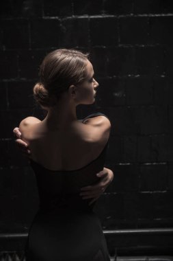 Tam arka pozisyonda ayakta büyüleyici dansçı