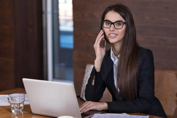 Smiling woman using a cellphone in an office — Stock Photo, Image