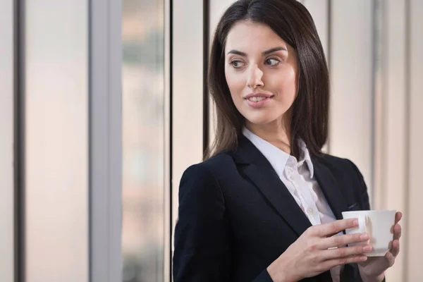 Brünette Frau trinkt Kaffee im Büro — Stockfoto