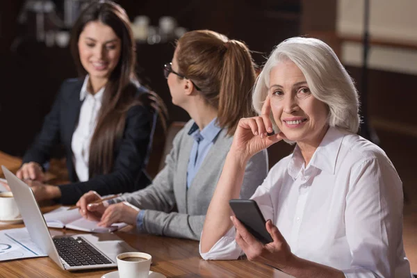 Elderly woman posing with her young colleagues — Stock Photo, Image