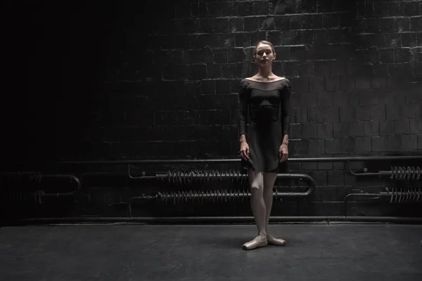 Estable joven bailarina de pie cerca de la pared oscura — Foto de Stock