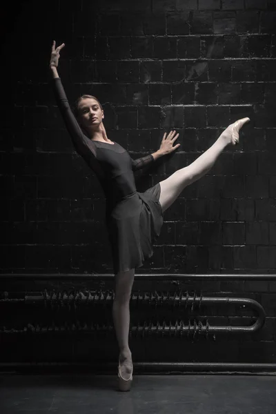 Entrenamiento de bailarina encantadora cerca de la pared negra —  Fotos de Stock