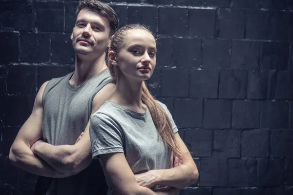 Jonge dansers die permanent in de buurt van de zwarte muur met gekruiste armen — Stockfoto