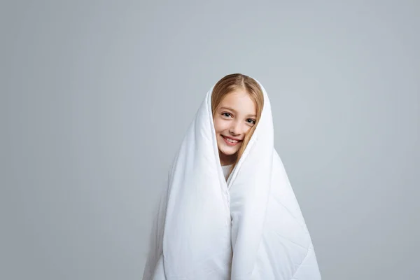 Menina positiva cobrindo heself com cobertor — Fotografia de Stock