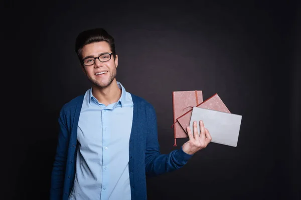 Pleasant smiling man holding diaries. — Stock Photo, Image