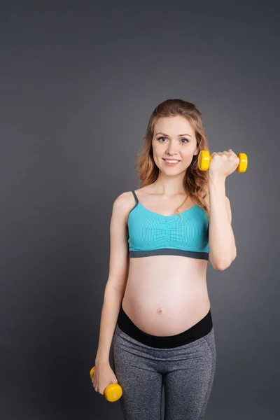 Belle sportive soulevant les haltères dans la salle de gym — Photo