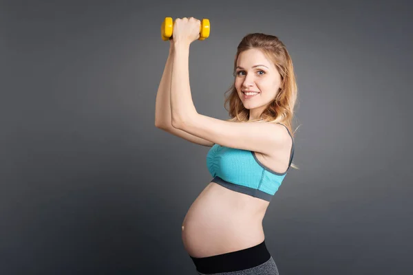 Беременная девочка занимается фитнесом с гантелями — стоковое фото
