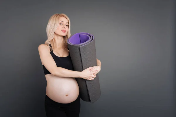 Mulher bonita enigmática com tapete de fitness em mãos — Fotografia de Stock