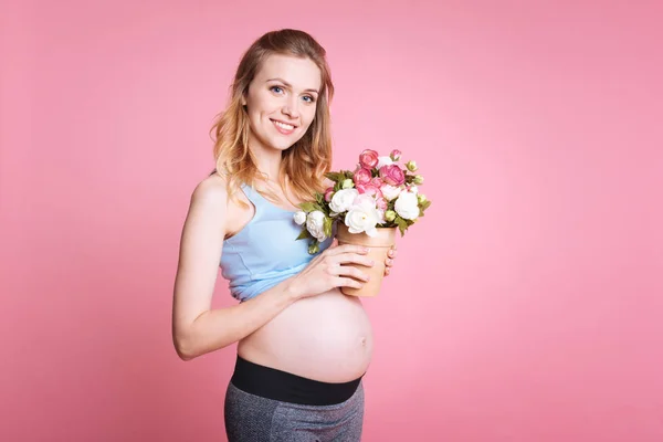 Vacker ung gravid kvinna som håller blommor — Stockfoto