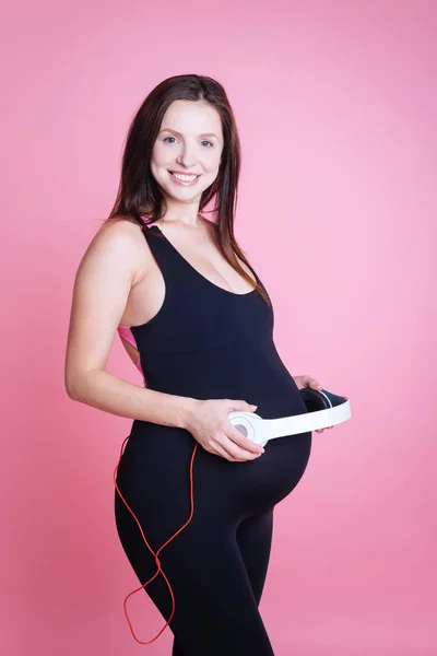 Femme enceinte mettant des écouteurs sur son ventre — Photo