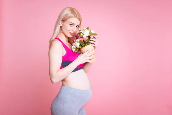 花束の臭いがする妊娠中の美しいブロンドの女の子 — ストック写真