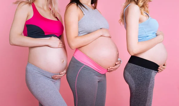 Tři těhotné ženy dotýkání bříšky baby — Stock fotografie