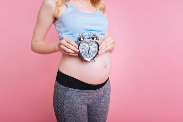 Närbild av väckarklocka över baby bump — Stockfoto