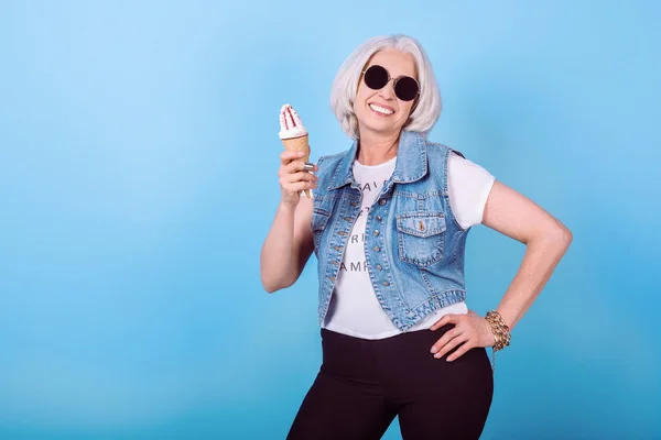 Стильная пожилая женщина держит мороженое и улыбается . — стоковое фото