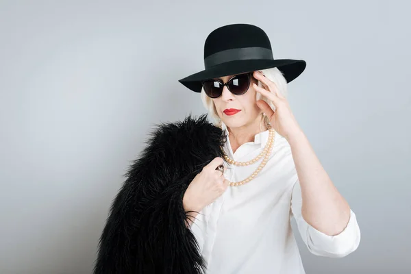 Mujer mayor grave tocando gafas de sol . — Foto de Stock