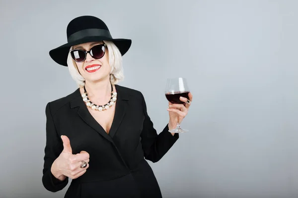 Чарівна старша жінка посміхається і п'є вино . — стокове фото