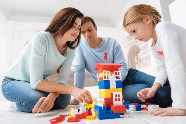 Familia seria y reflexiva construyendo una construcción de juguete — Foto de Stock