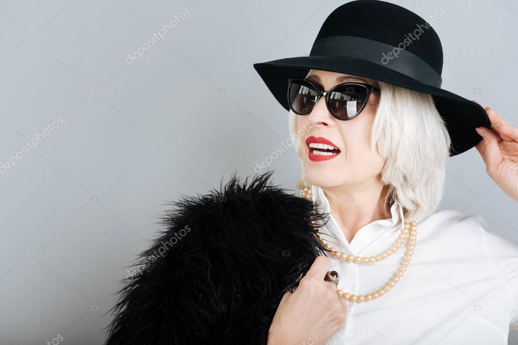 Attractive senior woman opening touching hat.