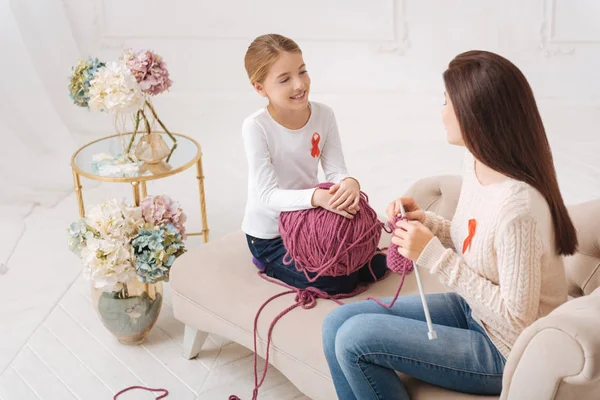 Cheerful cute mother and daughter knitting together