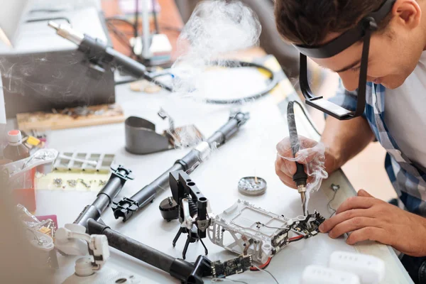 Hardworking man soldering drone details attentively — Stock Photo, Image