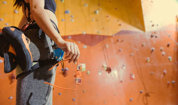 Primer plano de la mujer equipada de pie detrás de la pared de escalada . — Foto de Stock