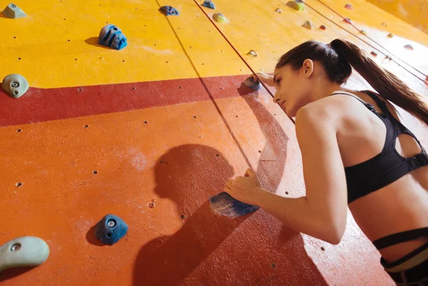 Vacker kvinna klättring upp på väggen i gymmet — Stockfoto