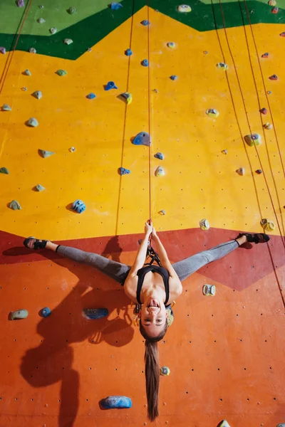 Mujer alegre haciendo un truco en la pared de escalada —  Fotos de Stock