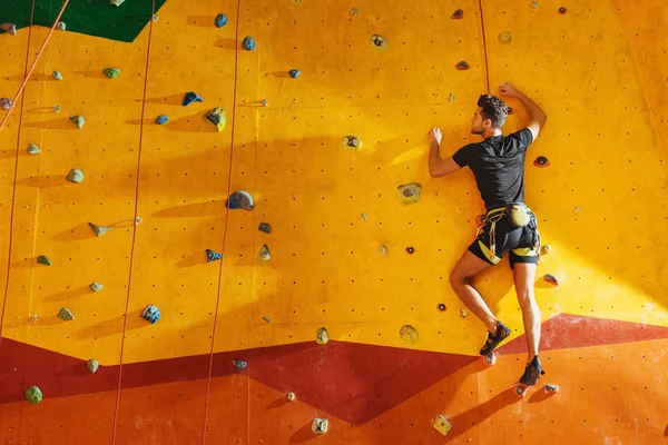 Junger Mann klettert mit Ausrüstung die Wand hinauf — Stockfoto