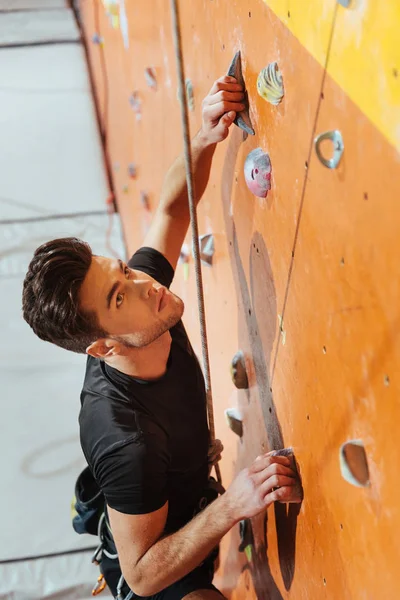 Young man climbing up the wall in gym — Stock Photo, Image