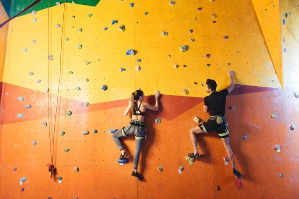 Giovane uomo e donna che si arrampicano sul muro — Foto Stock